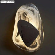 Modern nordic sconce light fixture with translucent swirling glass body and black metallic antique layered accents
