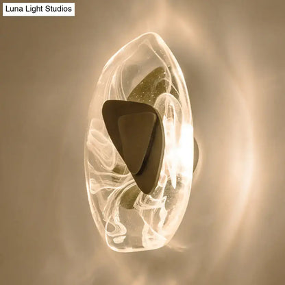 A modern nordic sconce light fixture with a clear glass shell, swirling white patterns, and black metallic antique accent