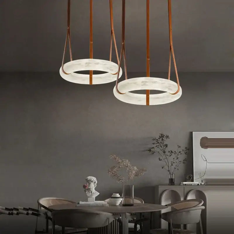 Two minimalist modern opal glass ring marble chandelier pendant lights with white marble rings and tan leather straps