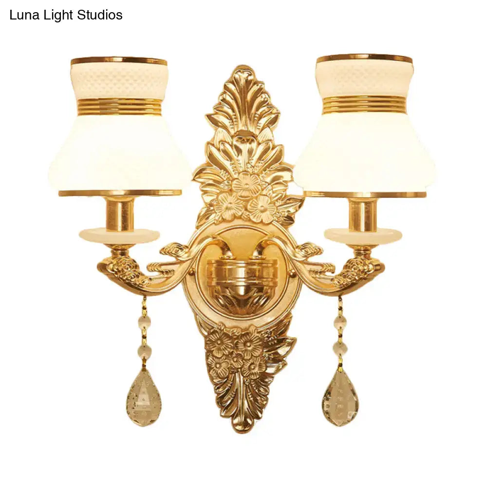 Modern ornate gold wall light with two cream frosted glass shades and crystal teardrop pendants for bedroom sconce