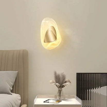 Modern oval crystal wall lamp with a translucent warm acrylic shell and metallic cone for bedroom use