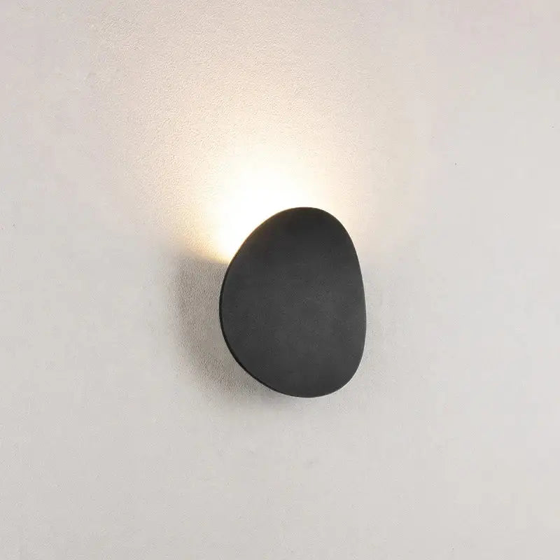Modern oval gray and dark gray led wall lamp with black smooth pebble-shaped led wall sconce emitting warm glow