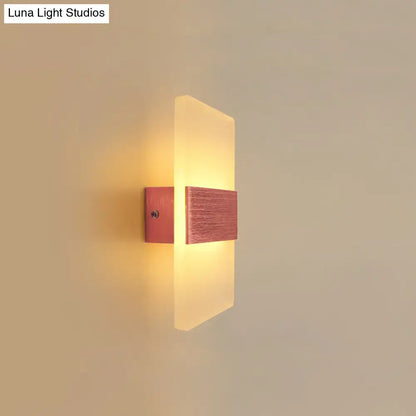 Modern oval rectangular convex led wall sconce with frosted glass and brushed copper accents emitting warm amber glow