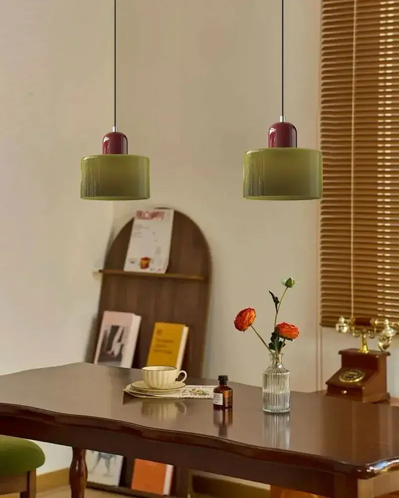 Two olive-green cylindrical pendant lights with burgundy stained glass shade tops for kitchen and dining room use