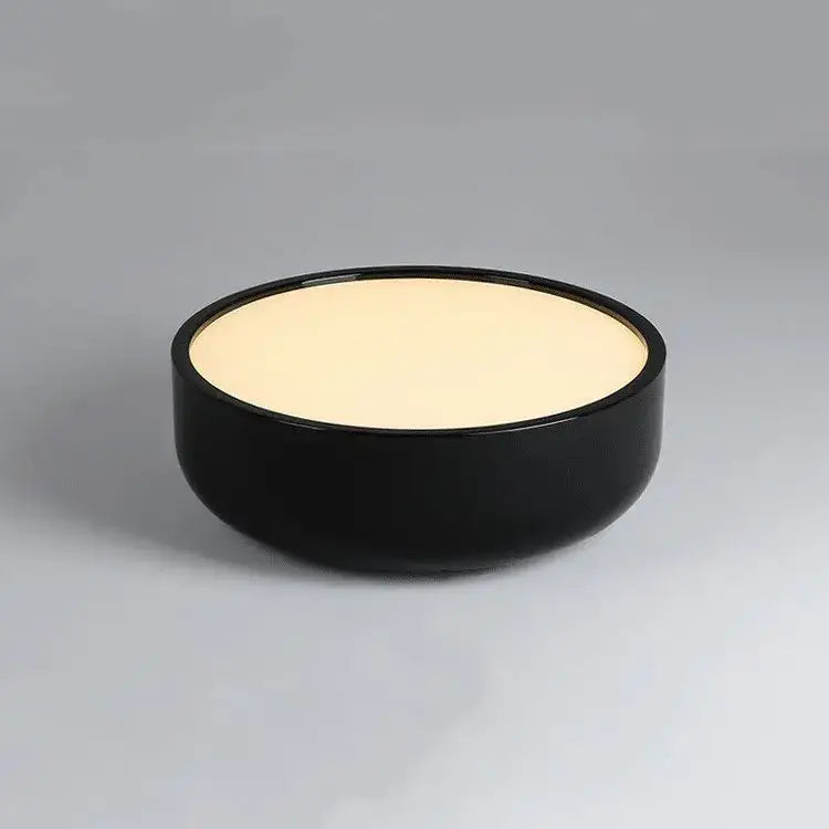 Black ceramic bowl with smooth glossy finish and cream interior paired with modern pastel pink and teal decorbites circular led ceiling light