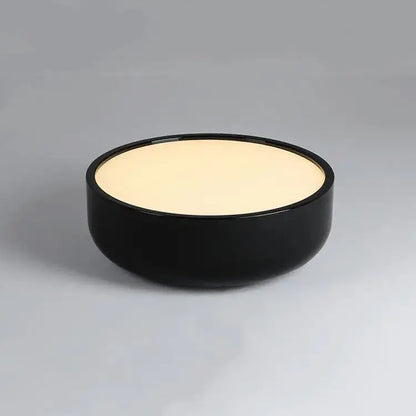 Black ceramic bowl with smooth glossy finish and cream interior paired with modern pastel pink and teal decorbites circular led ceiling light