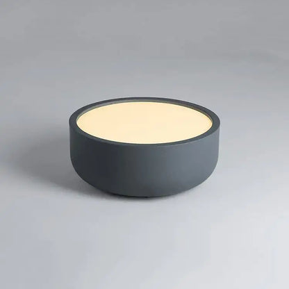 Modern pastel pink and teal circular led ceiling light with a dark gray circular table lamp featuring a cream illuminated top