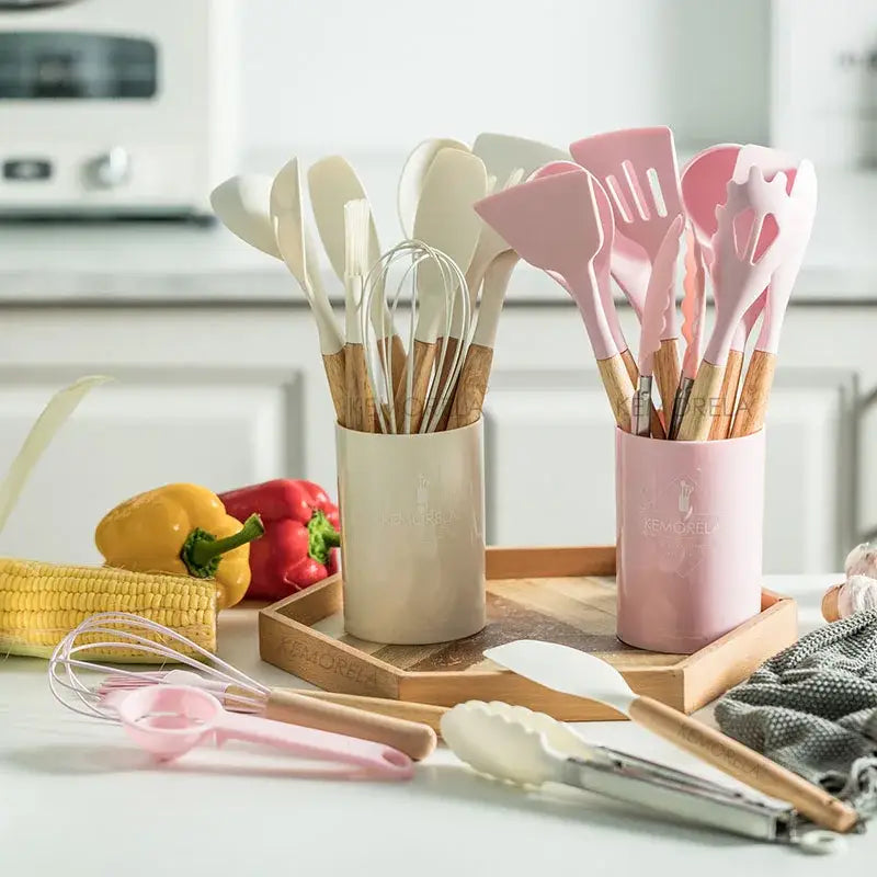 Modern pastel silicone kitchen utensil set with pink and white silicone-coated wooden handles in matching holders