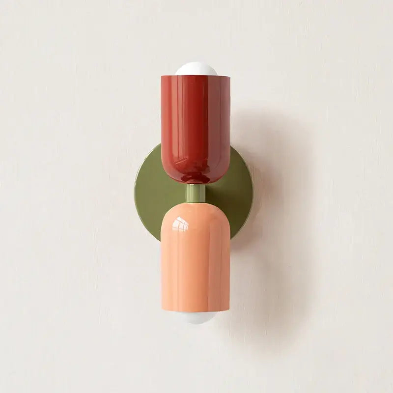 A modern two-tiered led wall light with glossy terracotta and matte peach shades on an olive green base by decorbites led wall