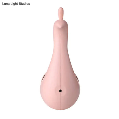 A sleek matte pink silicone modern peach peacock wall sconce with rounded body and top handle for bedroom rainbow projection