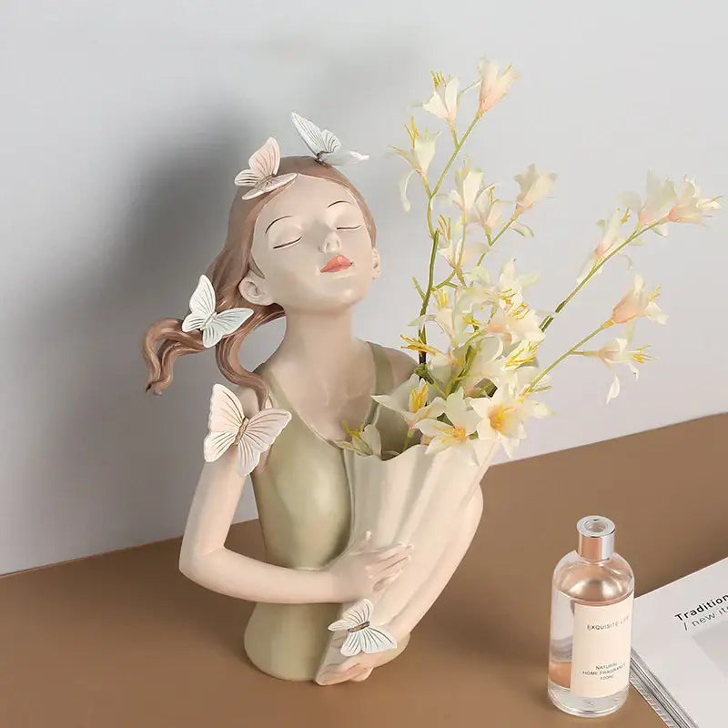 A delicate beige butterfly girl resin figure with white butterfly details holding pale yellow flowers on a gold tray