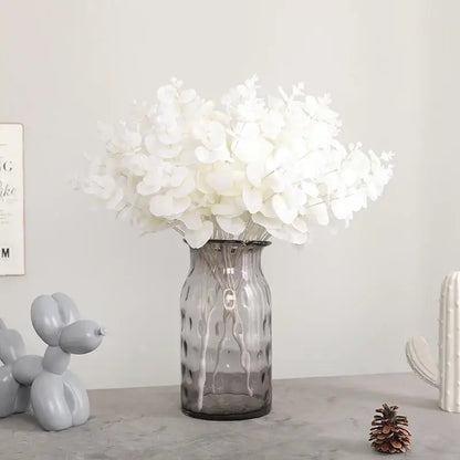 Modern pink living room glass vase with translucent gray ribbed surface holding a white eucalyptus flower arrangement