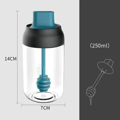 A clear glass seasoning bottle with teal and black lid and integrated teal honey dipper in modern pink glass set