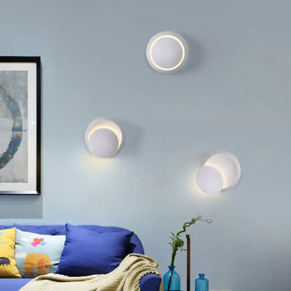 Three modern white circular wall sconces with glowing led rings.