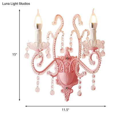 Modern pink metallic scroll arm wall lamp with crystal droplets and two candle-shaped bulbs for bedroom sconce lighting