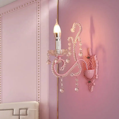Modern pink metallic scroll arm wall lamp with crystal accents and candle-style bulb for bedroom sconce lighting