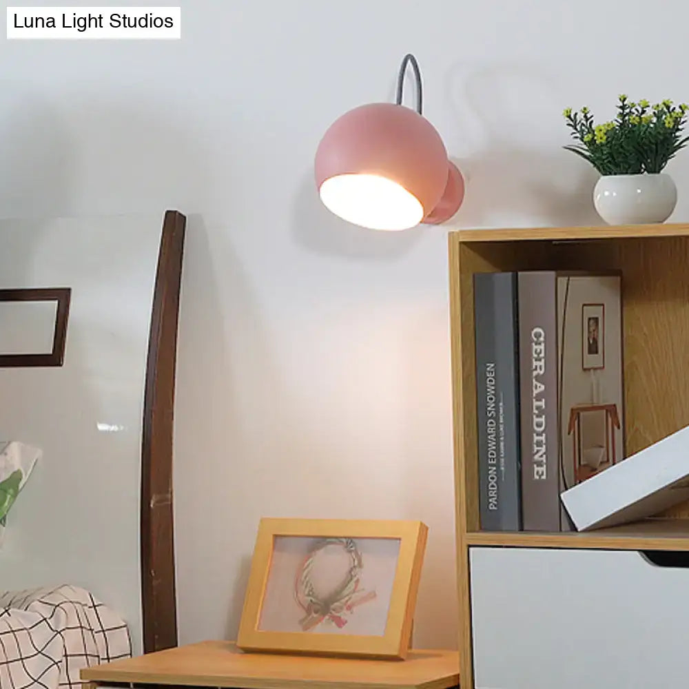Modern pink spherical wall lamp with curved black metal arm and flexible cord ideal for living room wall light