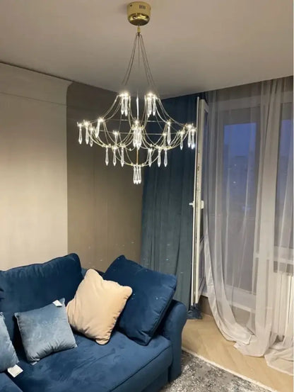 Modern polished steel pendant light with gold-toned frame and crystal pendants illuminated for dining room use
