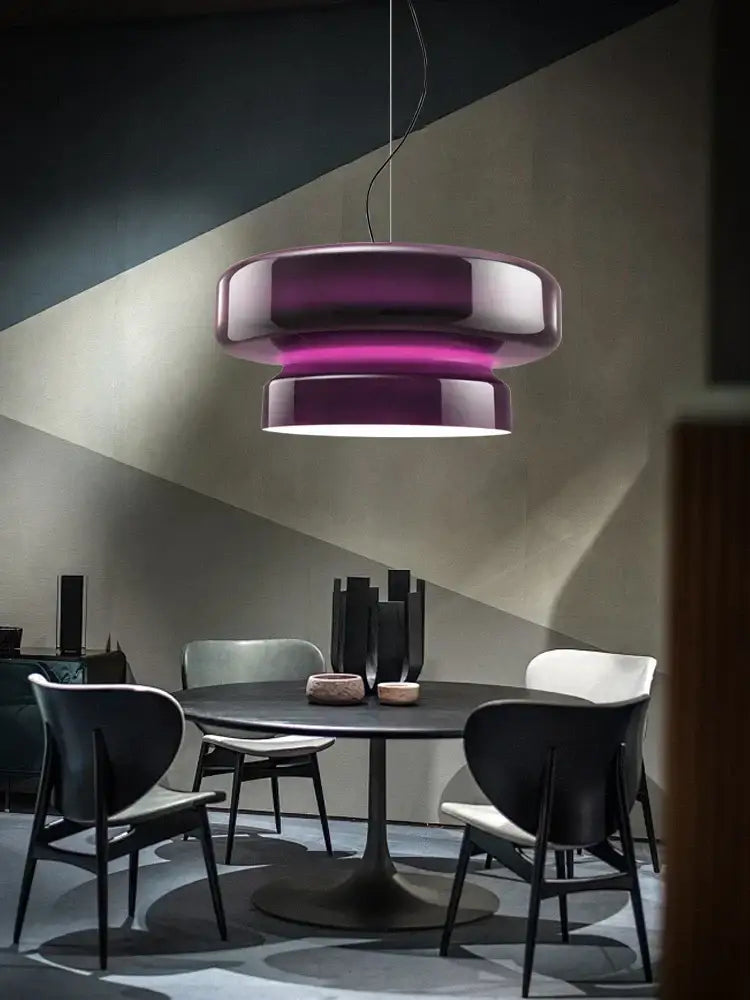 A sleek modern pendant light with a glossy purple and white decorbites italian glass finish above dining table