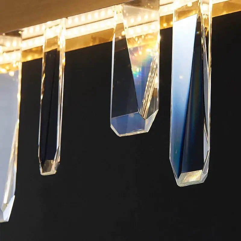 Clear faceted crystal pendants hang from a modern rectangle gold frame of DecorBites™ Kyala gold crystal chandelier