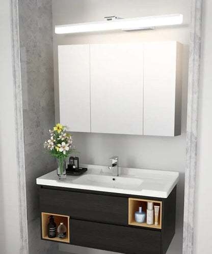Modern rectangular acrylic golden mirror cabinet light above white and dark wood bathroom vanity with open shelving