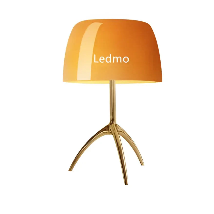 Modern table lamp with orange glossy glass shade and gold-toned tripod base for bedroom lighting