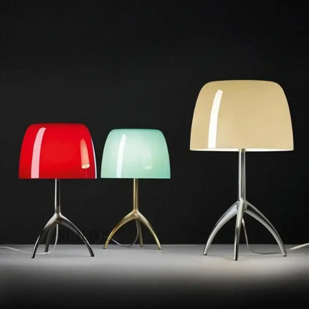 Three modern table lamps with red green and beige glass shade on polished metal tripod bases for bedroom use