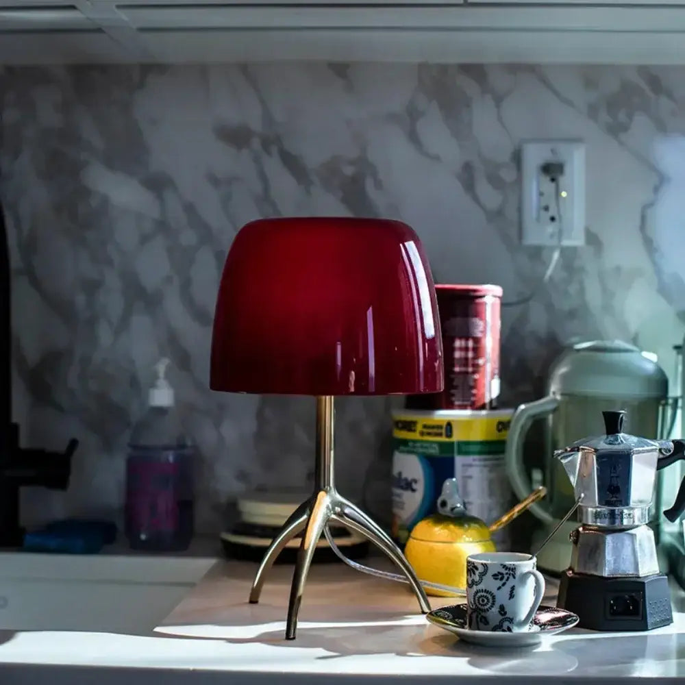 Modern red green and beige glass shade table lamp with a glossy red dome glass shade and metallic tripod base for bedroom use