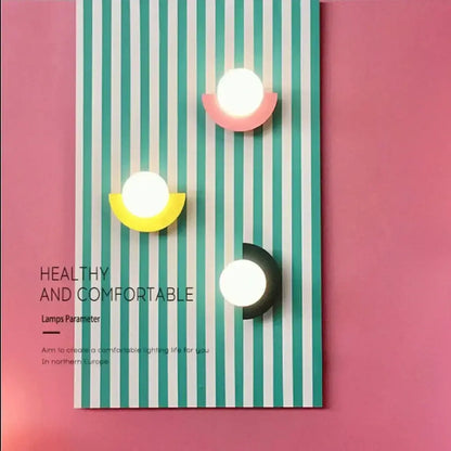 Three modern wall lamps with circular white glass ball led lights and colorful pink yellow and black decorbites glass ball bases