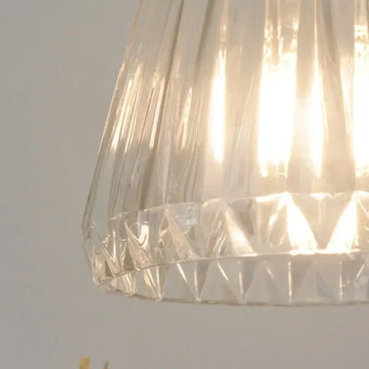 Modern ribbed clear glass led pendant light with a conical faceted lampshade and intricate cut patterns by decorbites