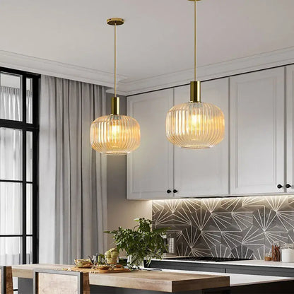 Two elegant gold-toned light chandeliers with ribbed amber glass colorful led pendants for dining room lighting