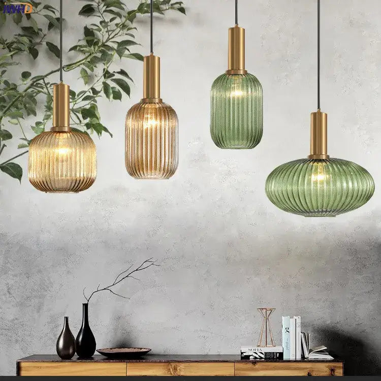 Four modern ribbed glass pendant lights with brass stems in amber, bronze, and green hues for dining room use