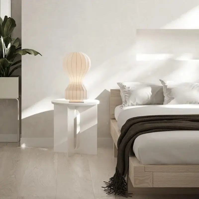 A cream-colored modern ribbed white ceramic table lamp with a softly glowing light ideal for bedroom decorbites gatto silk table