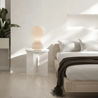 A cream-colored modern ribbed white ceramic table lamp with a softly glowing light ideal for bedroom decorbites gatto silk table