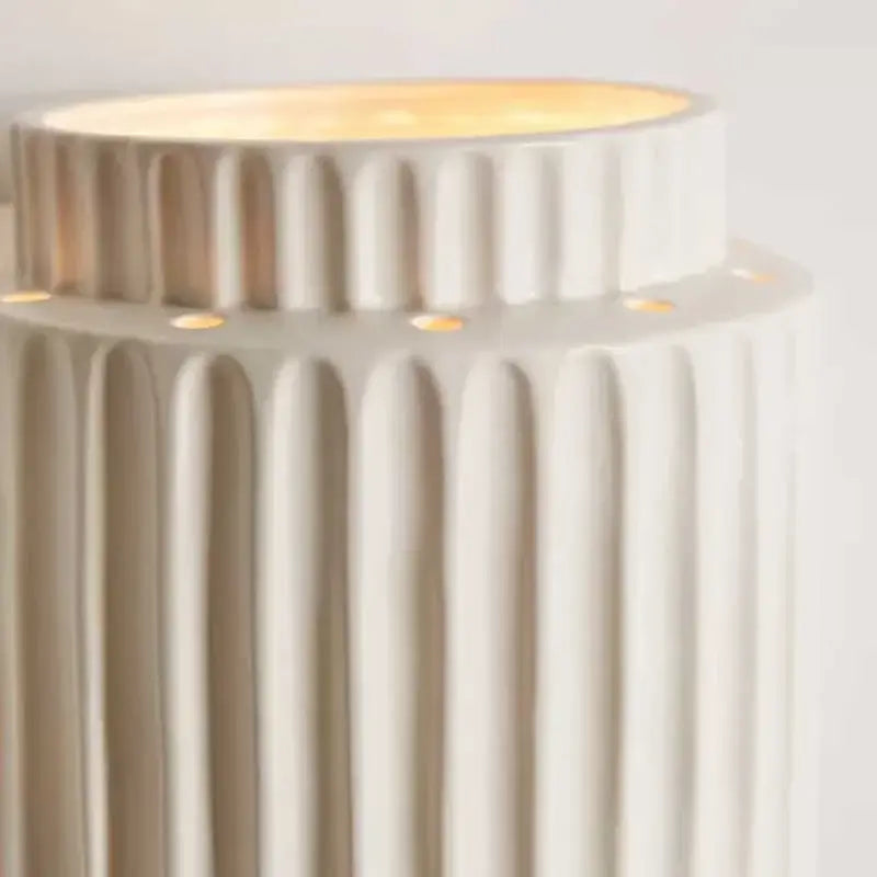 Cream white resin wall lamp with vertical ridges and warm glowing top for bedroom decorbites cream white lighting
