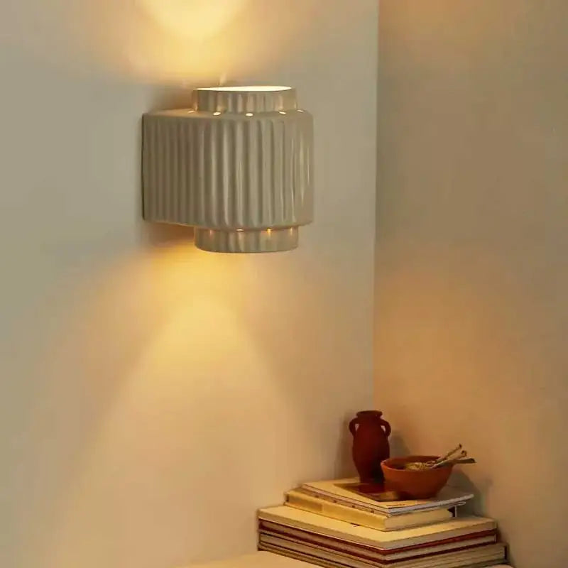 A sleek cream white resin wall lamp with vertical ridges and tiered design for modern bedroom decorbites lighting