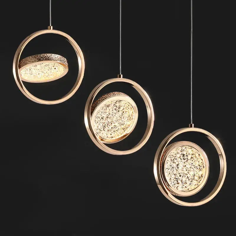 Three modern gold-toned circular pendant lights with textured crystal surfaces for a gold acrylic led chandelier
