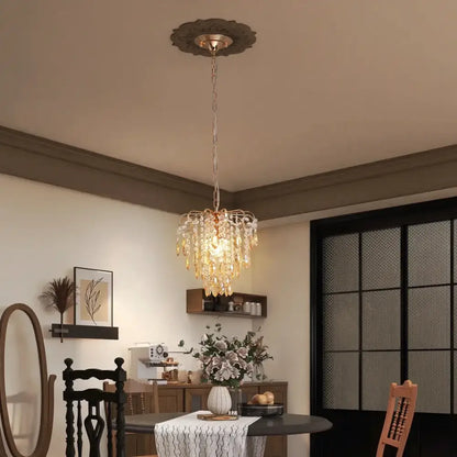A modern rose gold pendant light with amber crystal led droplets hanging from a decorative ceiling plate