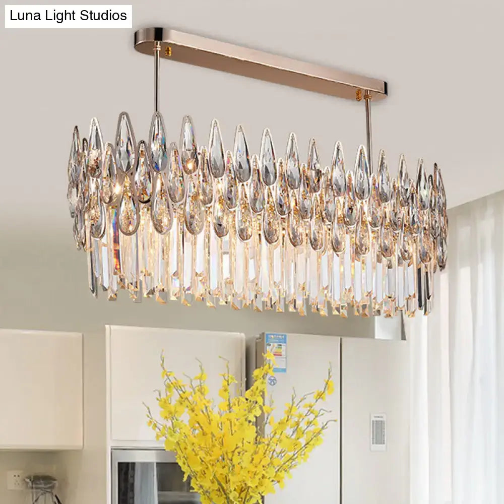 A modern rose gold crystal island lamp with a rectangular frame and cascading oval clear crystal pendants