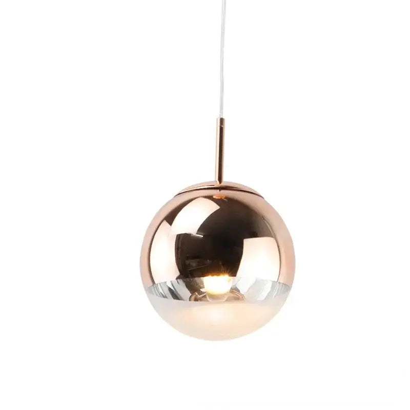 A modern rose gold and frosted glass ball pendant light featuring a polished spherical shade for kitchen decorbites