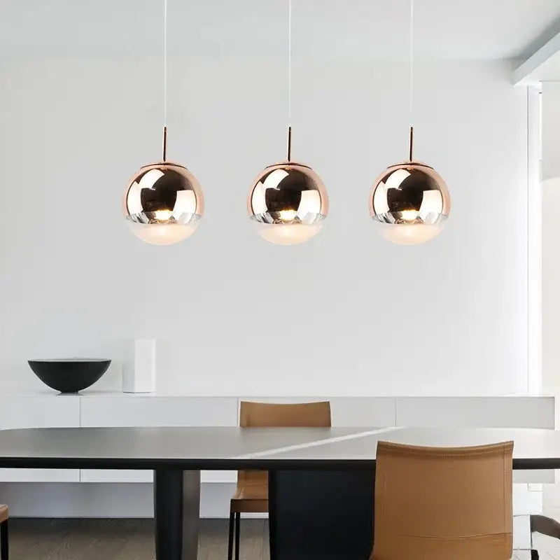 Three sleek rose gold glass ball pendant lights hang in a modern dining space decorbites glass ball fixture