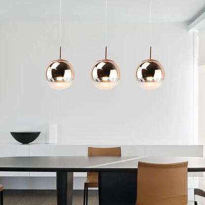 Three sleek rose gold glass ball pendant lights hang in a modern dining space decorbites glass ball fixture