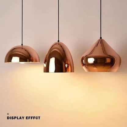 Three copper finished rose gold pendant lights with dome-shaped shades hang from black cords for dining room decorbites decor