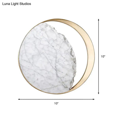 Modern round gold and white marble led wall sconce featuring a white marble slab with gray veining and a gold crescent frame