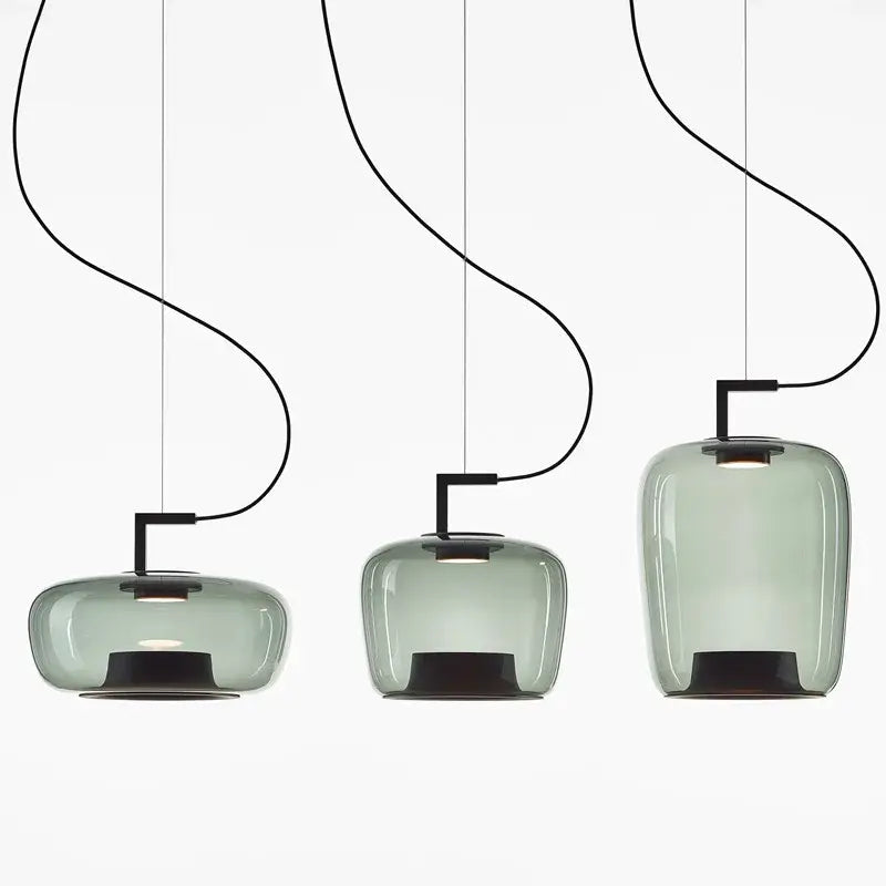 Three sleek translucent sage green glass pendant lamps with black metal fixtures ideal for dining room lighting