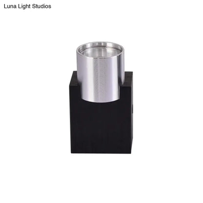 Modern silver aluminum cylindrical led wall light fixture mounted on a black base for bedroom accent lighting