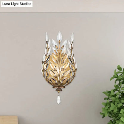 Gold-toned wall light with silver brass laurel design and crystal drop accents for bedroom lighting