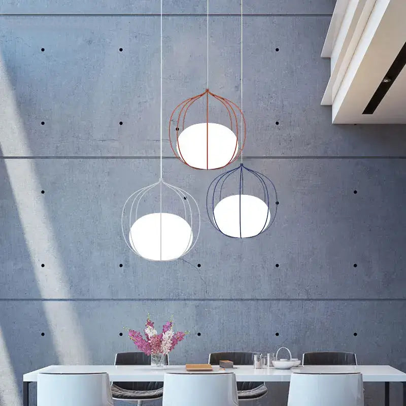 Three modern decorbites birdcage pendant lights with spherical white glass shades in silver and copper for dining room decor