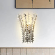 Modern silver crystal bead wall lamp featuring a polished gold-toned frame with cascading clear glass beads for bedroom use