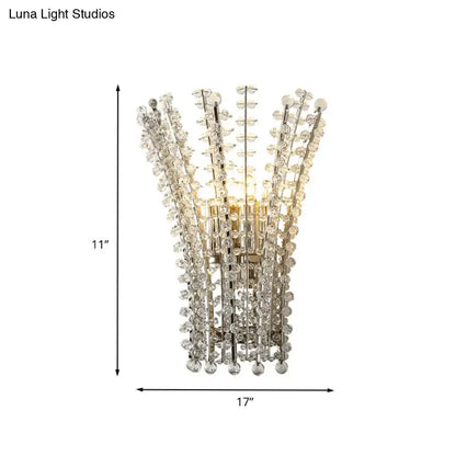 A modern silver crystal bead wall lamp with a chrome finish and cascading faceted crystal strands for bedroom use